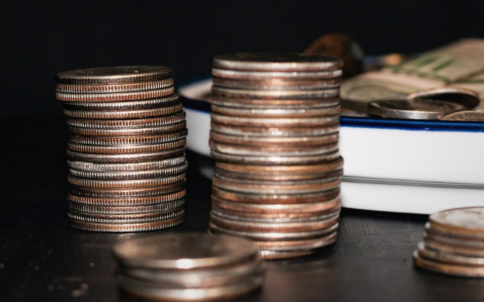 Stacks of coins arranged on a plate beside folded banknotes