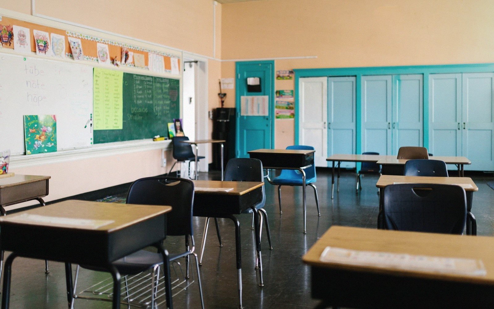 Empty classroom with rows of student desks facing a whiteboard and chalkboard